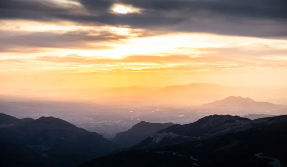 A breathtaking sunrise over a dramatic mountain landscape with a warm glow.