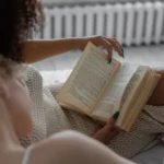 A person reading a book indoors, enjoying a relaxing and cozy environment.