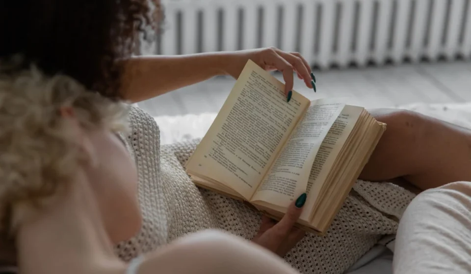 A person reading a book indoors, enjoying a relaxing and cozy environment.