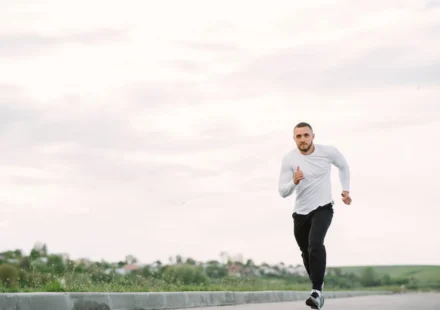 Adult man running on an empty road in casual sportswear, showcasing fitness and healthy lifestyle.
